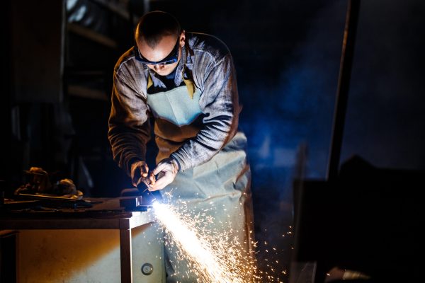 Worker cutting metal with plasma equipment on plant.